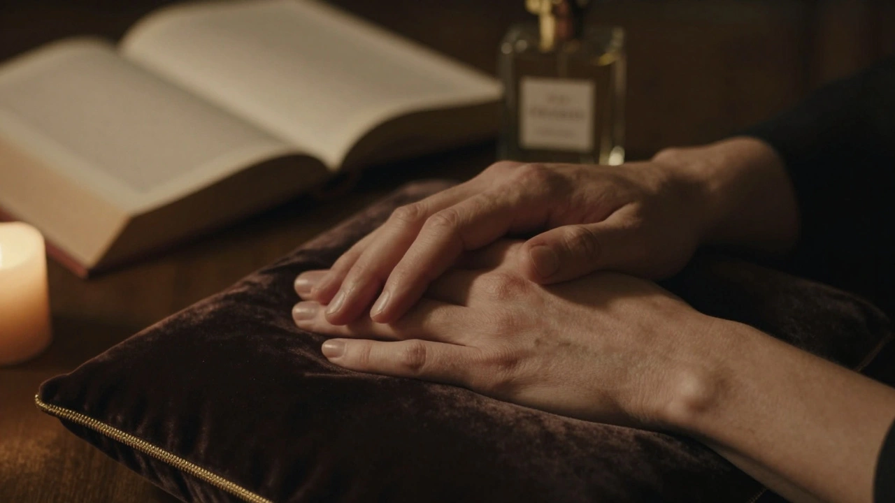 Deux mains se touchant doucement sur un coussin de velours, avec un livre et un parfum personnalisé en arrière-plan flou.