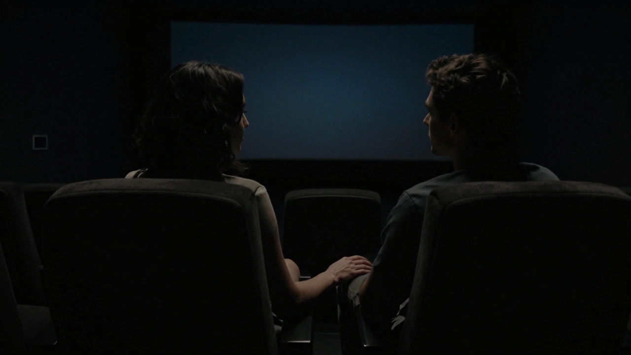 Un homme et une femme dans une salle privée de cinéma, la main d'elle posée sur sa cuisse dans le noir complet.